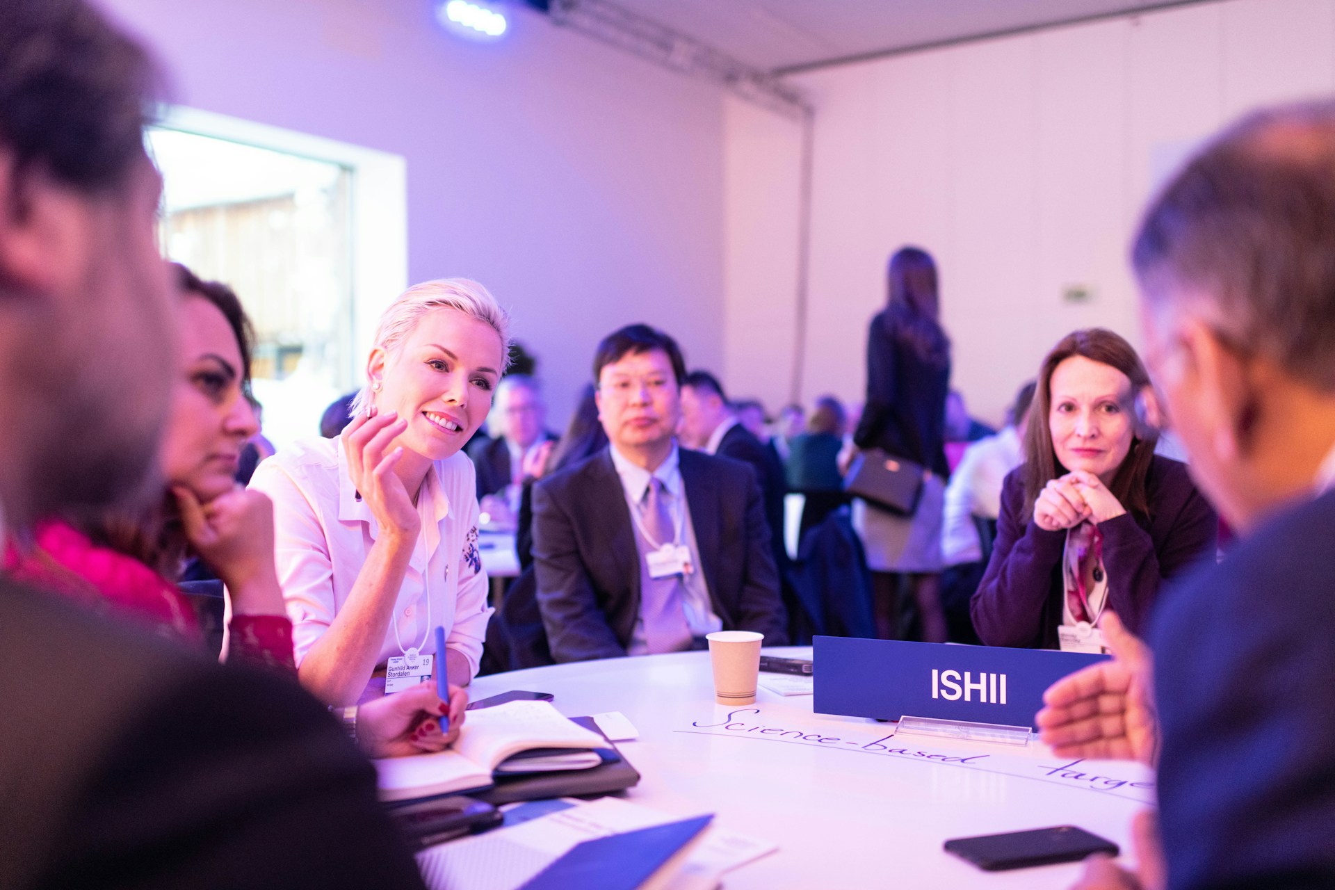 woman smiling and thriving at table with other business people at a big event